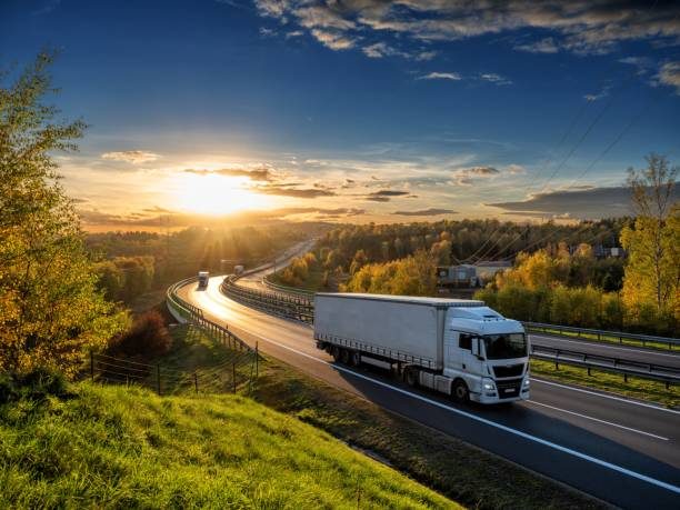 Camión de carga avanzando por una carretera al atardecer.